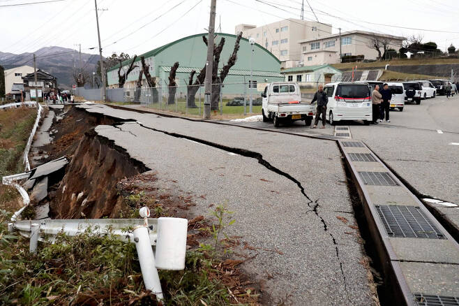 지난 1일 오후 7.5 규모의 대지진이 일본 이시카와현 노토 지역을 강타하면서 시민들이 와지마시(市)의 한 거리로 대피한 후, 인도 한 가운데 발생한 큰 균열 옆에 서 있는 모습. [AFP]