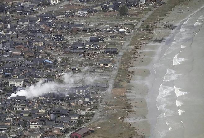 일본 이시카와현에서 지난 1일 발생한 강진으로 2일 스즈시의 해안가 일대 주택 등이 파손되고, 화재가 발생해 연기가 나고 있다. AP연합뉴스