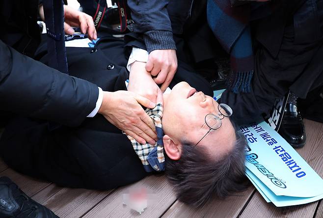 이재명 더불어민주당 대표가 2일 오전 부산 강서구 가덕신공항 부지를 둘러본 뒤 왼쪽 목 부위 피습을 당해 바닥에 누워 병원 호송을 기다리고 있다. [연합]