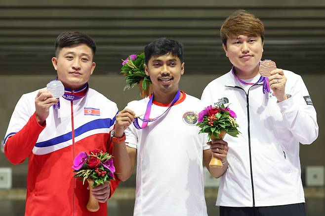 26일 중국 항저우 푸양 인후 스포츠센터에서 열린 제19회 항저우 아시안게임 남자 10ｍ 러닝타깃 혼합 개인전에서 동메달을 딴 정유진과 은메달을 딴 북한 권광일이 기념 촬영하고 있다. 가운데는 금메달을 딴 인도네시아 무함마드 세자테라 드위 푸트라./연합뉴스