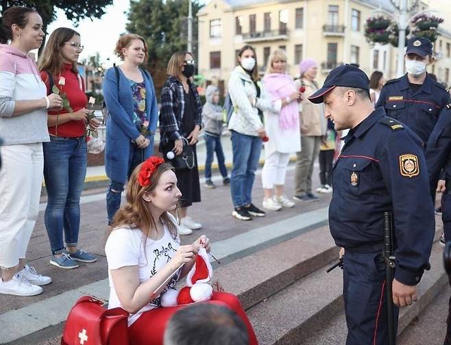 경찰이 다가오자 한 벨라루스 여성이 뜨개질하고 있다./트위터