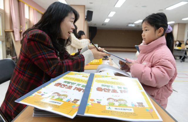 초등학교 신입생 예비소집일인 3일 오전 울산 중구 울산초등학교 가입학식에서 예비 초등학생이 교사로부터 교재를 전달받고 있다. 뉴시스