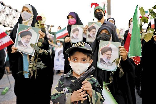 라이시 당선에 환호하는 지지자들 - 세예드 에브라힘 라이시 이란 대선 후보의 당선이 확정된 19일 수도 테헤란에서 열린 지지자들의 축하집회에서 한 어린아이가 장난감 총을 들고 있다. /AP 연합뉴스