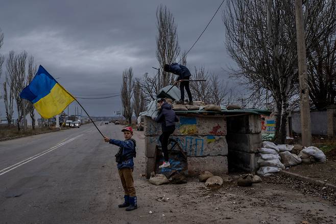 23일(현지 시각) 우크라이나 남부 헤르손의 한 버려진 검문소에서 한 우크라이나 어린이가 국기를 흔들며 놀고 있다. 이날 러시아군은 수도 키이우를 포함해 우크라이나 전역의 주요 시설에 미사일 총 67발을 발사했다. 이 때문에 우크라이나 곳곳에서는 물론 인접국 몰도바에서도 정전사태가 야기됐다./AP 연합뉴스