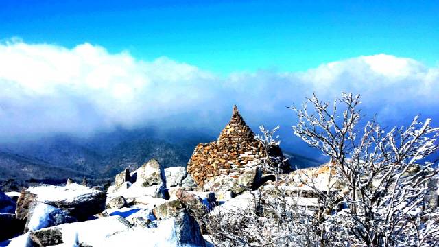 ▲ 태백산 문수봉의 설경. 돌탑 너머로 천제단 능선과 멀리 함백산의 원경이 한눈에 들어온다.