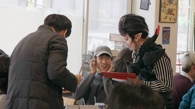 A player interacts with a drag performer serving as the game master at the cafe's "Dungeons & Drag-ons" event. Game masters help direct and organize the story and play in a tabletop role-playing game. (The Korea Herald)
