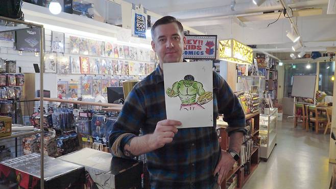 Croner holds up his drawing of the Hulk holding the cafe's signature cheeseburgers. The week's "Drink & Draw" event was held under the theme of participants' favorite superhero's life in Korea. (The Korea Herald)