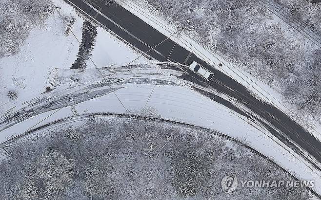 '빙판길 조심하세요' (대구=연합뉴스) 윤관식 기자 = 10일 대구 군위군 부계면 남산리 한 도로가 빙판길로 변한 가운데 한 차량이 주행하고 있다. 2024.1.10 psik@yna.co.kr