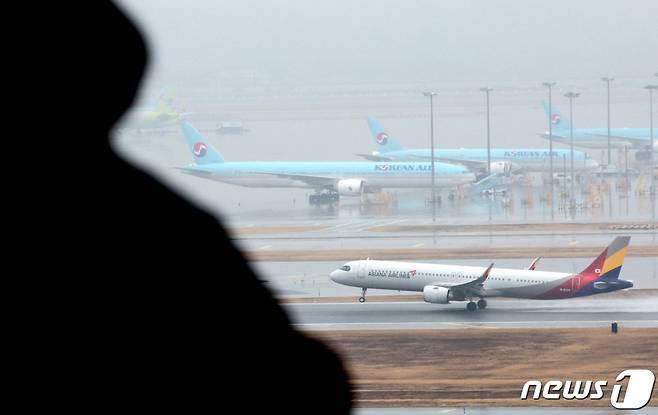 (인천공항=뉴스1) 장수영 기자 = 14일 오후 인천국제공항 계류장에 세워진 대한항공 항공기 앞으로 아시아나 항공기가 이륙하고 있다.   유럽연합(EU) 반독점 규제 당국은 지난 12일 대한항공과 아시아나항공 인수를 조건부 승인할 예정이라고 밝혔다.   EU는 두 회사가 합병 시 화물 부문을 분리 매각하고 유럽 4개 도시 여객 노선을 매각하는 것을 조건으로 내세웠다. 2024.1.14/뉴스1  Copyright (C) 뉴스1. All rights reserved. 무단 전재 및 재배포,  AI학습 이용 금지.