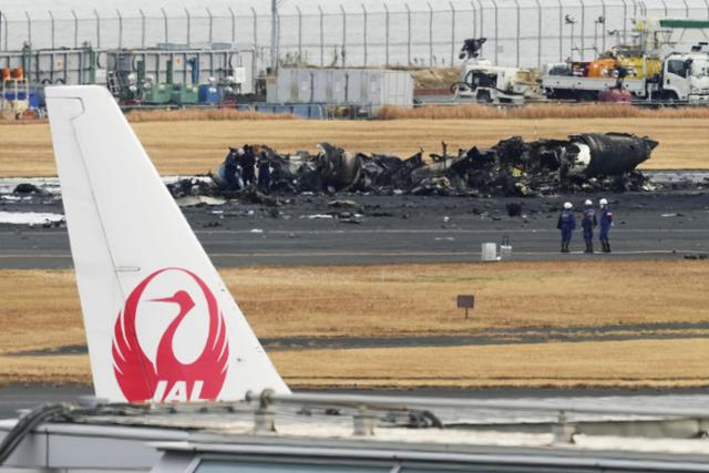 3일 일본 도쿄 하네다공항 활주로에 충돌사고로 불에 탄 해상보안청 항공기 잔해가 보인다. 앞쪽은 일본항공 로고가 달린 항공기 꼬리날개. 도쿄= AP 연합뉴스