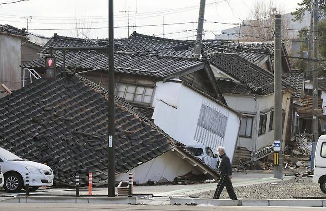 지난 11일 일본 이시카와현 와지마시에서 한 남자가 무너진 집들 사이를 걷고 있다. 뉴시스