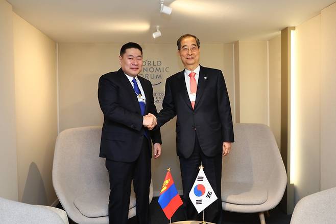 한덕수 국무총리가 17일(현지시간) 스위스 다보스포럼에서 롭상남스라이 어용에르덴 몽골 총리와 악수하고 있다. 두 명 모두 포럼 내 최고 등급인 하얀색 골드 배지를 목에 걸고 있다. 총리실 제공