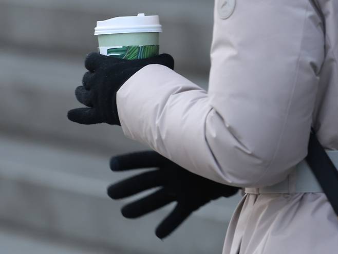 한 시민이 커피를 들고 이동하고 있다. 연합뉴스