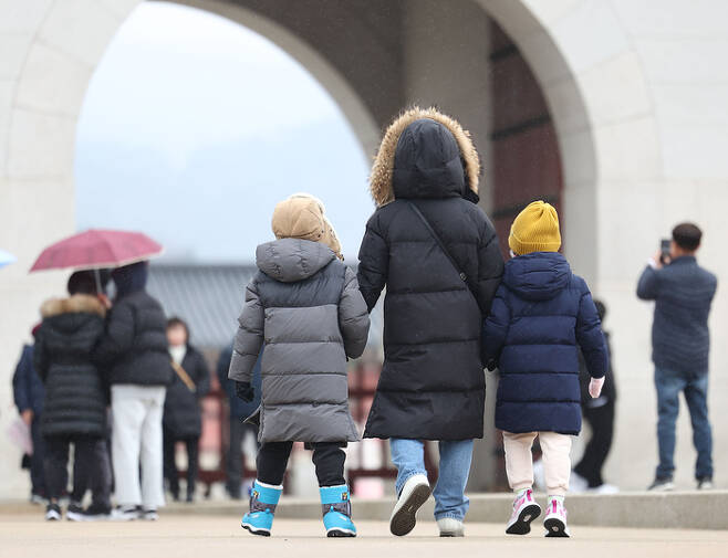 지난 21일 오후 서울 경복궁을 찾은 가족이 두꺼운 옷차림을 한 채 걸어가고 있다. 연합뉴스