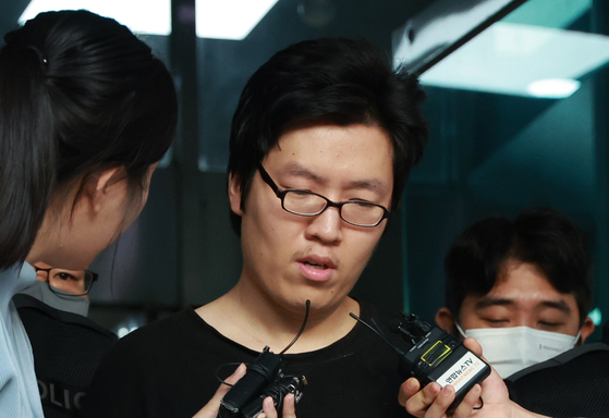 Choi Yoon-jong, center, answers reporters' questions as he is escorted from Seoul Gwanak Police Precinct to face questioning by prosecutors on Aug. 25. Choi was sentenced to life in prison on Monday for murdering a woman he attacked on a hiking trail in Sillim-dong, Gwanak District, southern Seoul. [YONHAP]