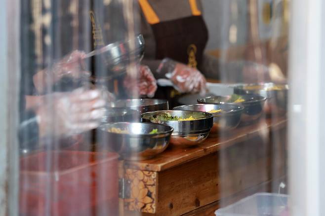 봉사자들이 배분한 비빔밥이 방풍문 너머로 보이고 있다. 김혜윤 기자