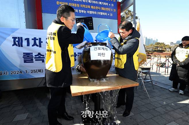 이필수 대한의사협회 회장을 비롯한 의협 집행부가 25일 서울 용산 대통령실 앞에서 정부의 의대정원 증원 추진 규탄 집회를 열고 의대 정원 확대는 건강보험료 재정 파탄이라고 주장하며 ‘밑 빠진 독’에 물을 붓는 퍼포먼스를 하고 있다. 2024.01.25. 조태형 기자