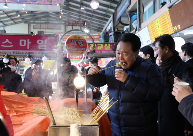 윤석열 대통령이 25일 경기도 의정부시 의정부제일시장을 찾아 어묵을 먹고 있다. 의정부=연합뉴스