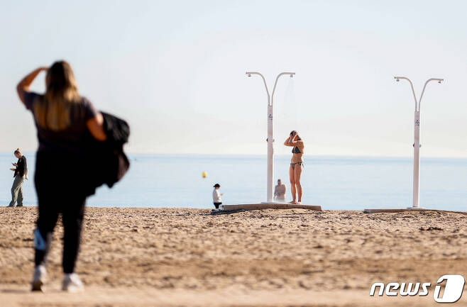 스페인 발렌시아 해변에서 한 여성이 수영복 차림으로 샤워를 하고 있다. ⓒ 로이터=뉴스1 ⓒ News1 박형기 기자