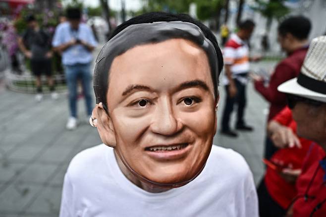 태국 방콕 대법원 앞에서 탁신의 지지자가 탁신의 가면을 쓰고 지지 시위를 하고 있다.(사진=AFP)