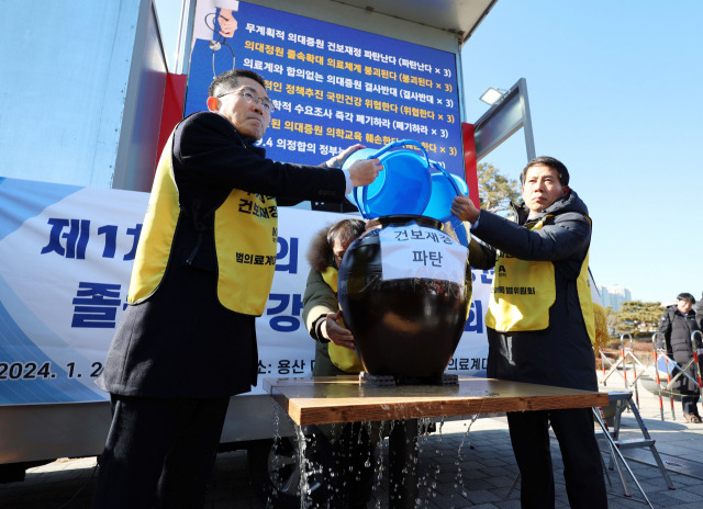 이필수 범의료계대책특별위원회 위원장(왼쪽)과 참석자들이 25일 용산 대통령실 앞에서 정부의 의대 증원 추진을 규탄하는 집회를 열고 구멍 난 항아리에 물을 붓는 퍼포먼스를 하고 있다. 연합뉴스