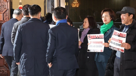 1일 국회에서 열린 더불어민주당 의원총회 앞에서 정의당과 노동계 관계자들이 회의장으로 향하는 의원들을 향해 중대재해처벌법 유예 반대 입장을 피력하고 있다. 연합뉴스