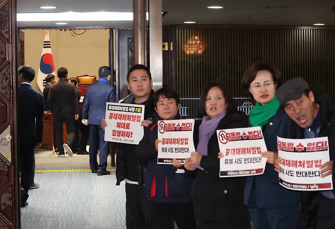 1일 국회에서 열린 더불어민주당 의원총회 앞에서 정의당과 노동계 관계자들이 회의장으로 향하는 의원들을 향해 중대재해처벌법 유예 반대 입장을 피력하고 있다. ⓒ연합뉴스