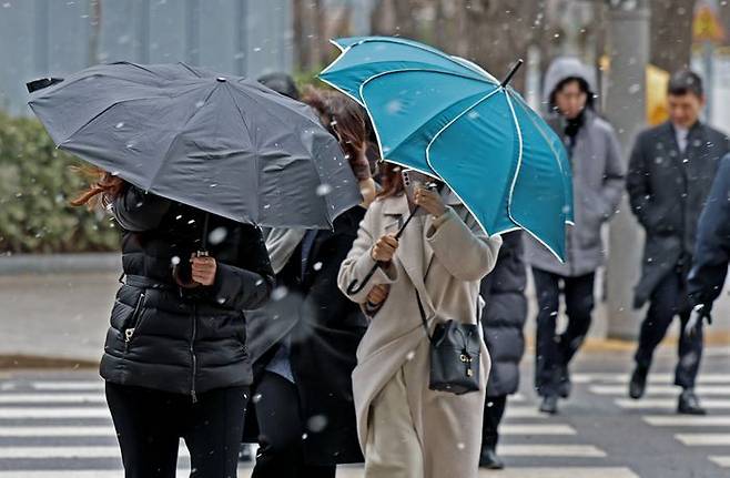 오후 한때 진눈깨비와 돌풍이 몰아친 5일 서울 시내 한 거리에서 시민들이 우산을 쓰고 이동하고 있다.ⓒ뉴시스