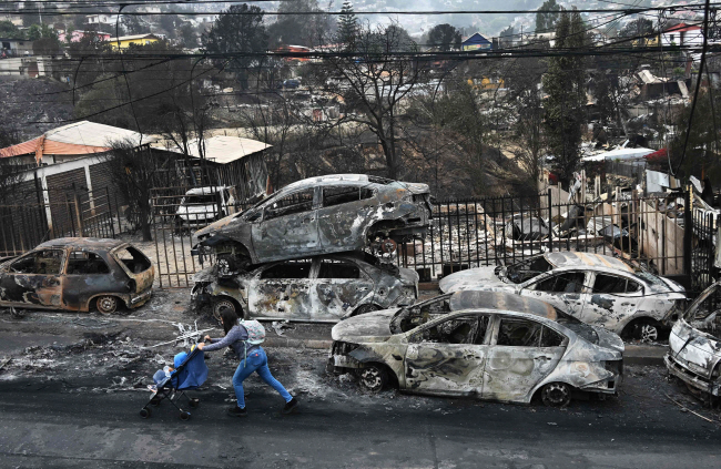 불 타버린 휴양지 칠레의 대표적 휴양지인 비냐델마르 지역이 산불로 큰 피해를 입은 가운데 한 여성이 4일 불에 탄 자동차들 사이로 아이를 태운 유모차를 끌고 지나가고 있다.  AFP 연합뉴스