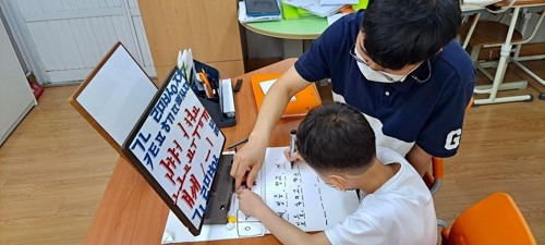 초등학교의 한 남성 교사가 한 아이를 지도하고 있다. [사진 = 연합뉴스]