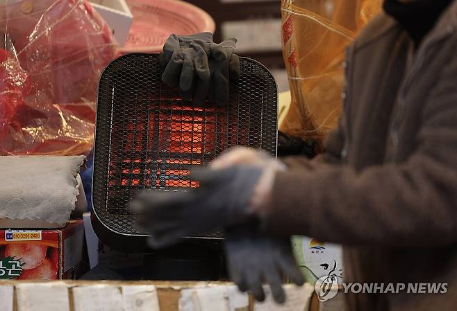 손이 시리다 (서울=연합뉴스) 박동주 기자 = 1일 오후 서울의 한 전통시장에서 한 상인이 난로에 올려둔 장갑을 끼고 있다.
    설 명절을 앞두고 소상공인과 전통시장 체감 경기가 약 2년 만에 가장 나쁜 것으로 조사됐다. 경기 침체에 따른 소비 감소가 가장 주요한 요인으로 꼽혔다. 2024.2.1 pdj6635@yna.co.kr