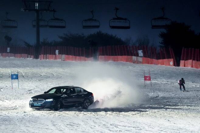 BMW 뉴 i5 M60 xDrive와 스키 선수가 활강 및 회전 대결을 펼치는 영상 화면.