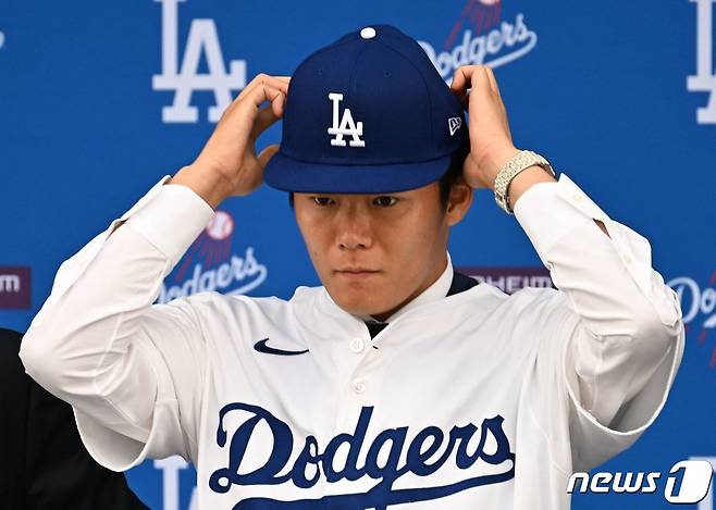 일본인 투수 야마모토 요시노부가 27일(현지시간) 역대 MLB 투수 최고 보장액인 12년 3억2500만 달러를 받고 캘리포니아주 로스앤젤레스 다저스타디움에서 열린 입단식서 다저스 유니폼과 모자를 착용하고 있다. 2023.12.28 ⓒ AFP=뉴스1 ⓒ News1 우동명 기자