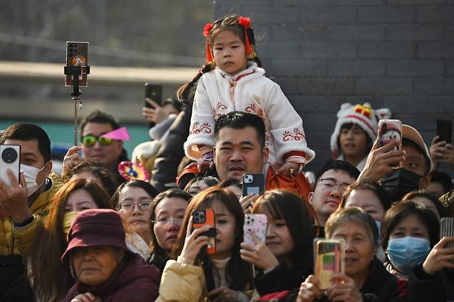 어린 딸을 목말 태운 아버지-12일 베이징에서 부녀가 '용춤' 공연을 보고 있다./AFP 연합뉴스