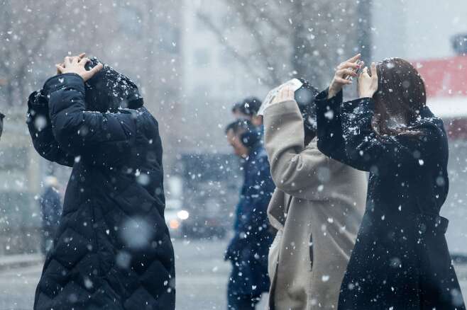 서울 지역에 눈이 내리는 지난달 17일 여의도에서 직장인들이 점심식사를 하기 위해 이동하고 있다. /뉴스1