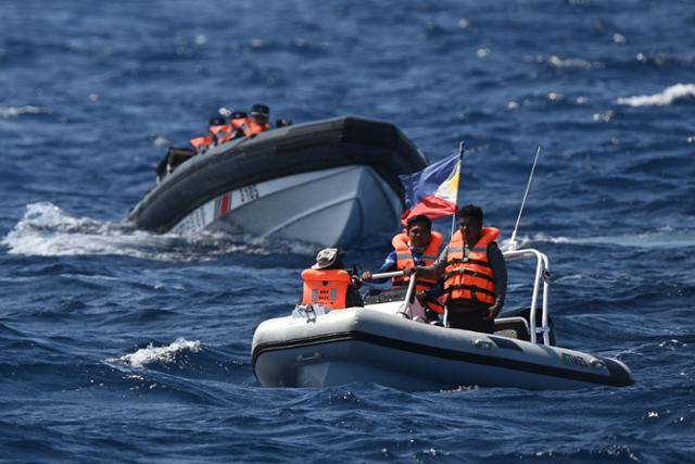 지난 16일 남중국해 스카버러 암초 인근 해역에서 필리핀 수산자원국 관계자(오른쪽)가 탄 보트를 중국 해경선이 바짝 쫓고 있다. AFP 연합뉴스