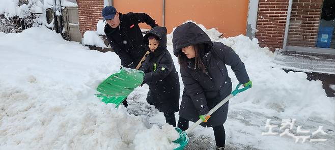 강릉 성산에 60cm가 넘는 폭설이 쏟아진 가운데 22일 오전 성산면의 한 가족이 상가 앞 눈을 치우고 있다. 전영래 기자