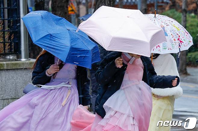 서울 지역에 눈이 내리는 21일 종로구 경복궁 인근에서 한복을 입은 시민들이 발걸음을 재촉하고 있다. 2024.2.21/뉴스1 ⓒ News1 안은나 기자