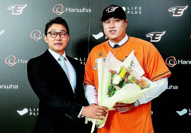 12년 만에 한국프로야구 친정팀 한화 유니폼을 다시 입은 류현진(오른쪽)이 22일 구단과 8년 총액 170억 원에 계약을 마친 뒤
박찬혁 대표이사에게서 꽃다발을 전달받았다. ‘8년 170억 원’은 한국 프로야구 역대 최대 규모 계약이다. 한화 제공