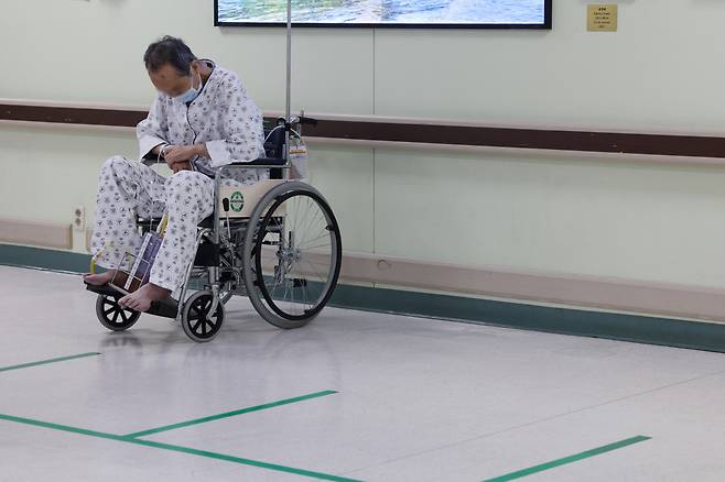 정부가 보건의료재난 위기경보를 최상위 단계인 '심각'으로 상향한 23일 서울의 한 대학병원에서 휠체어에 탄 환자가 고개를 숙이고 있다. [연합]