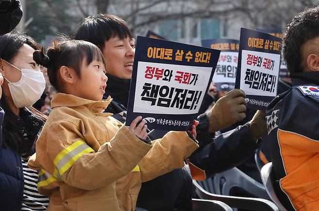 전국공무원노동조합 소방본부 소속 소방관들이 26일 오후 서울 영등포구 여의도 KDB산업은행 본점 앞에서 총궐기대회를 열어 소방 인력 증원과 소방 조직 국가직화 등을 촉구하고 있다. 한 소방관 가족이 함께 집회에 참석하고 있다. 신소영 기자 viator@hani.co.kr