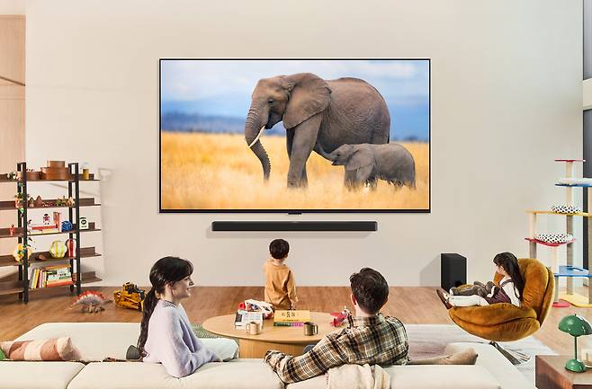 LG전자가 AI 성능을 강화한 신규 프로세서로 더 선명한 화질과 풍성한 공간 음향을 제공하는 2024년형 LG 올레드 TV와 QNED TV를 출시한다. 사진은 모델들이 2024년형 LG QNED TV로 콘텐츠를 즐기는 모습. [LG전자 제공]