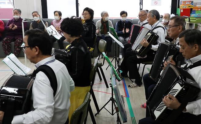 아코디언 봉사단원이 은빛사랑채에서 연주하는 동안 어르신들이 박수를 치며 흥겨워하고 있다.