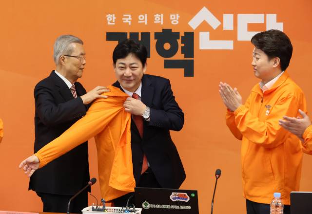 김종인 개혁신당 공천관리위원장이 4일 국회에서 열린 최고위원회의에서 영입 인재인 김범준 전 부산대학교 특임교수에게 당 점퍼를 입혀주고 있다. 오른쪽은 이준석 대표. 연합뉴스