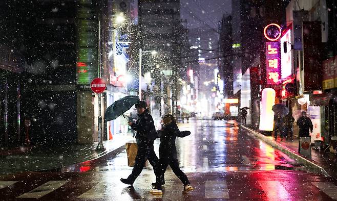 한 거리에서 우산을 쓴 시민들이 내리는 눈 사이를 걷고 있다. 뉴시스