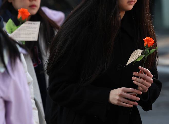 세계 여성의 날을 맞아 8일 오전 서울 서대문구 이화여대에서 학생들이 한국여성의전화 관계자들이 나눠준 장미꽃을 들고 가고 있다. 연합뉴스