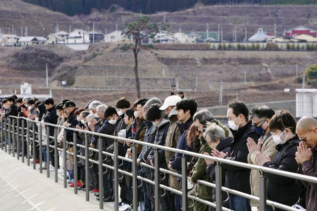 일본 이와테현 리쿠젠다카타 시민들이 11일 오후 2시 46분 동일본 대지진 발생 13주기를 맞아 희생자들을 기리며 묵념하고 있다. 리쿠젠다카타=AP 뉴시스