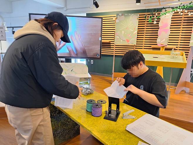 지난 9일 강원도 춘천시 ‘커먼즈필드 춘천’에서 열린 ‘경계선지능인 팝업 스토어’에서 현범(오른쪽)씨가 자신이 쓴 소설 일부를 출력해 시민들에게 나눠주기 위해 책 모양으로 접고 있다. 박수혁 기자