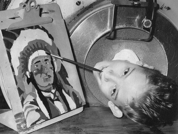 1955년 8월 아이언렁 안에서 머리만 내밀고, 입에 문 붓으로 그림을 그리는 폴 리처드 알렉산더/자서전 '강아지를 얻기 위한 3분'