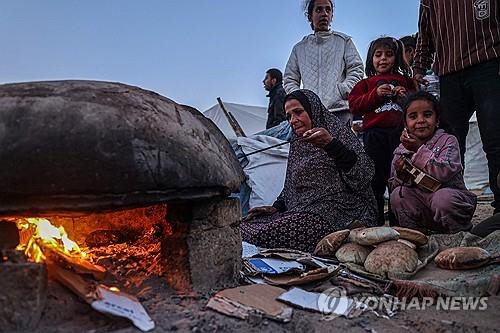 라마단 맞은 팔레스타인 가자지구 (라파 AFP=연합뉴스) 이슬람 금식성월 라마단 첫날인 11일(현지시간) 팔레스타인 가자지구 남부 라파에서 금식을 깨는 저녁 식사 이프타르 전 한 팔레스타인 피란민 여성이 빵을 굽고 있다. 
2024.3.11 photo@yna.co.kr